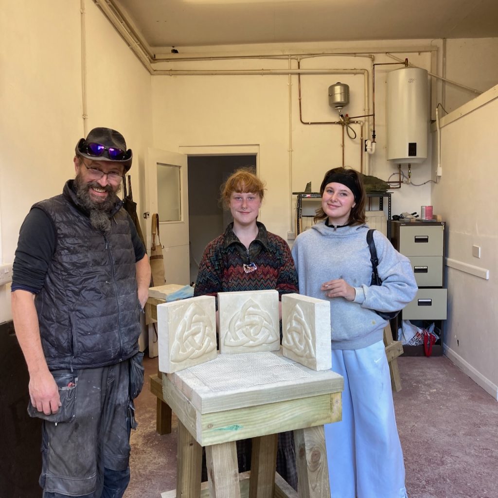 three people with completed stone carvings